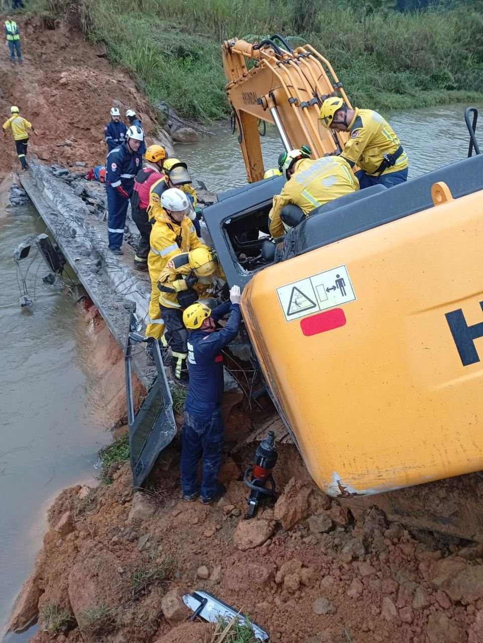 Bombeiros resgatam homem preso após retroescavadeira cair em ribanceira em Antônio Carlos